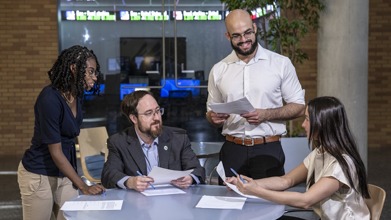 A group of students talking with a professor in front of a computer lab