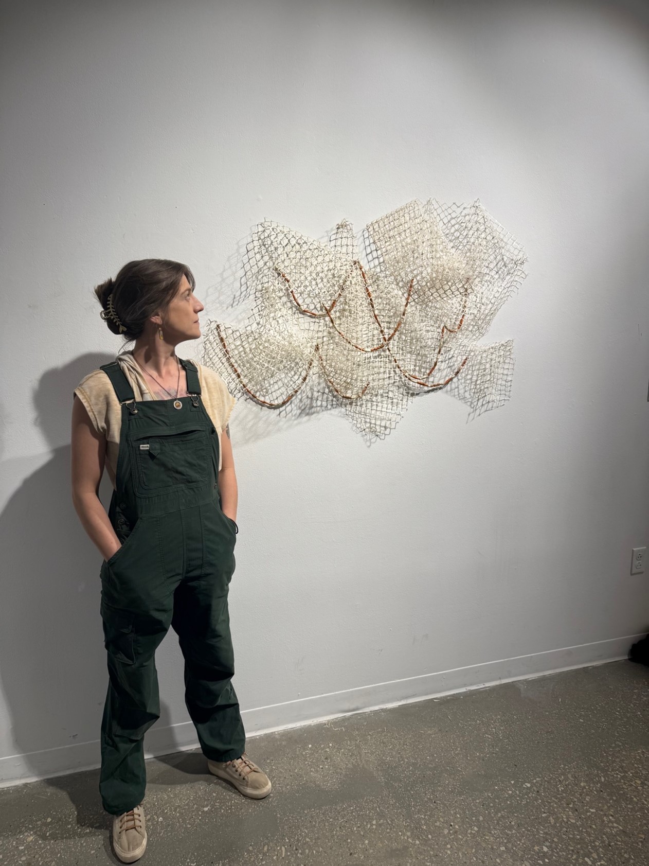 IADS Senior Erin McSweeny stands next to a laser-cut paper sculpture from her Digital Methods class in the sculpture critique space at UNT.